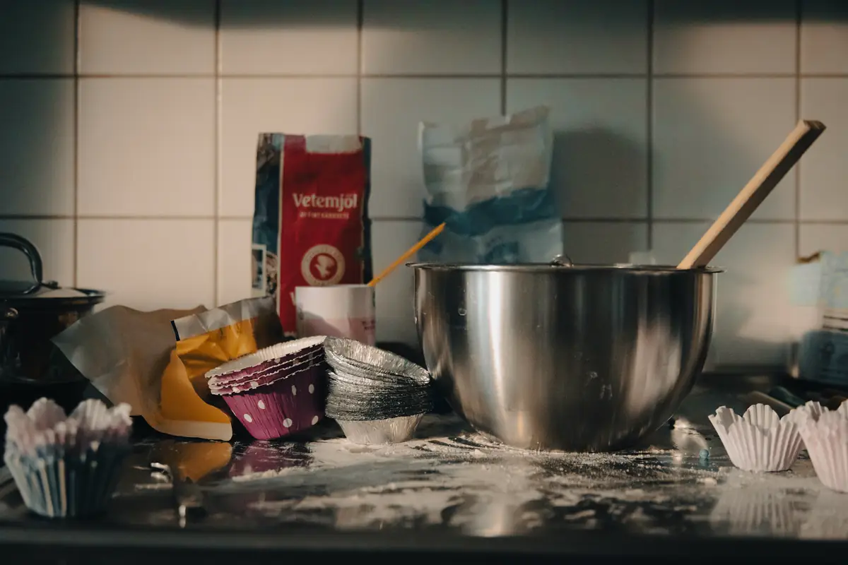 En bunke, muffinsformar och mjöl på en köksbänk.